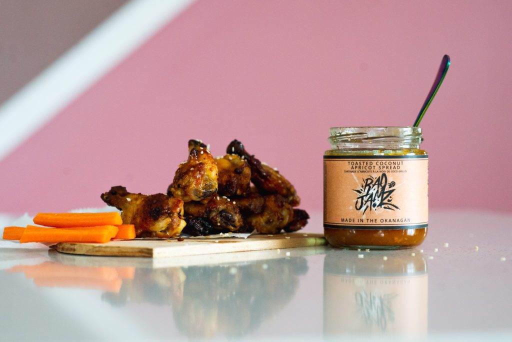 Chicken wings on a table with a jar of jam